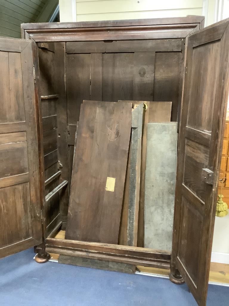 A large fruitwood double wardrobe / armoire, with twin carved panelled doors below a dentil frieze, raised on squat bun feet, 18th century, width 130cm, depth 62cm, height 198cm